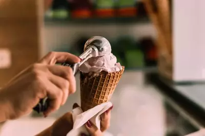 person scooping ice cream into a waffle cone
