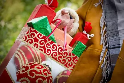 A woman holding Christmas gifts in a bag.
