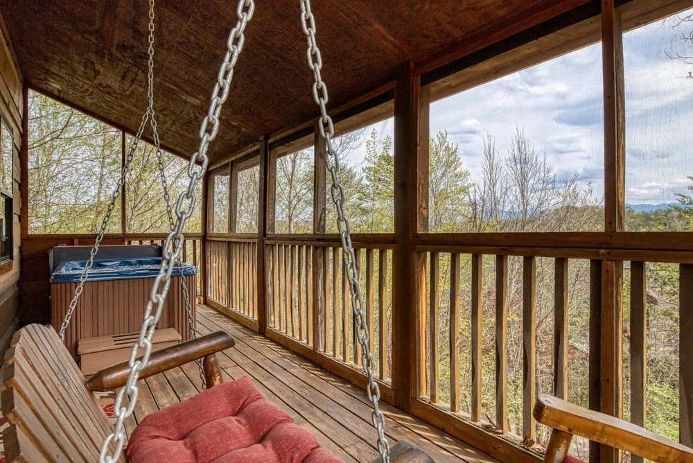 hot tub and porch swing facing mountain view on screened-in deck of Cozy Bear View