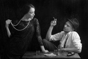 A couple posing for a 1920s-themed old time photo.