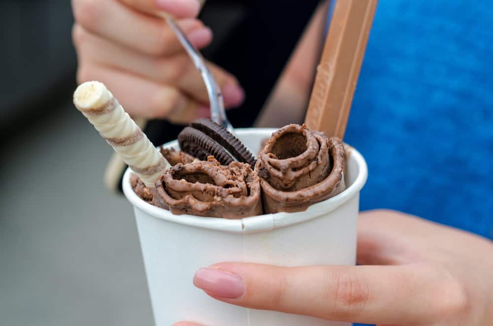A woman eating delicious rolled ice cream.