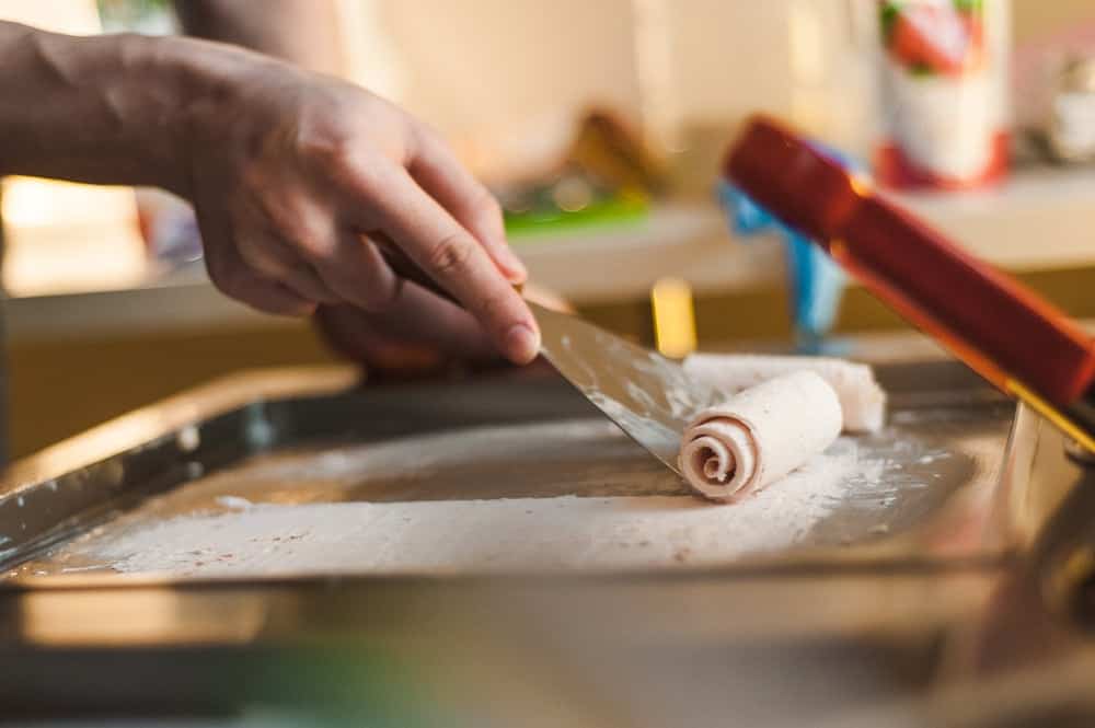 Ice cream being rolled on a pan.
