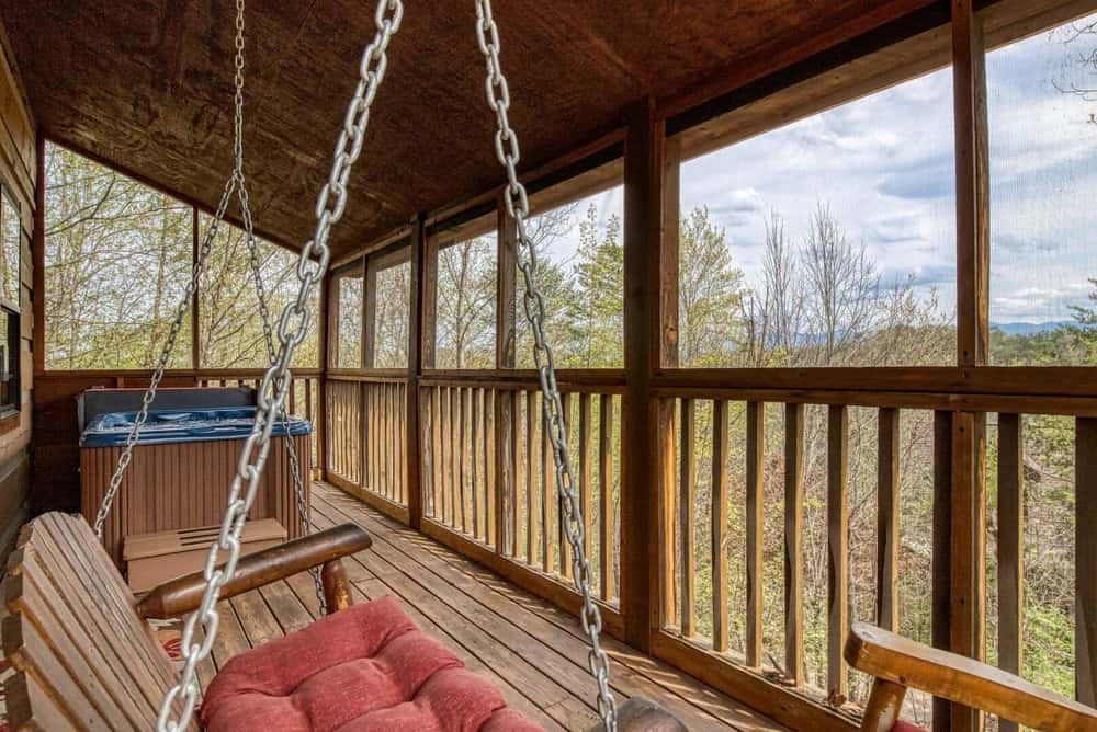 Porch swing and hot tub on deck with mountain view at Cozy Bear View cabin