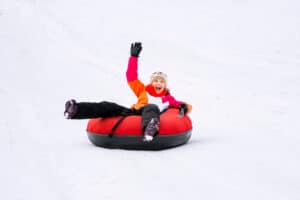 girl snow tubing down snow-covered hill