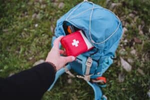 packing red first aid kit in hiking backpack